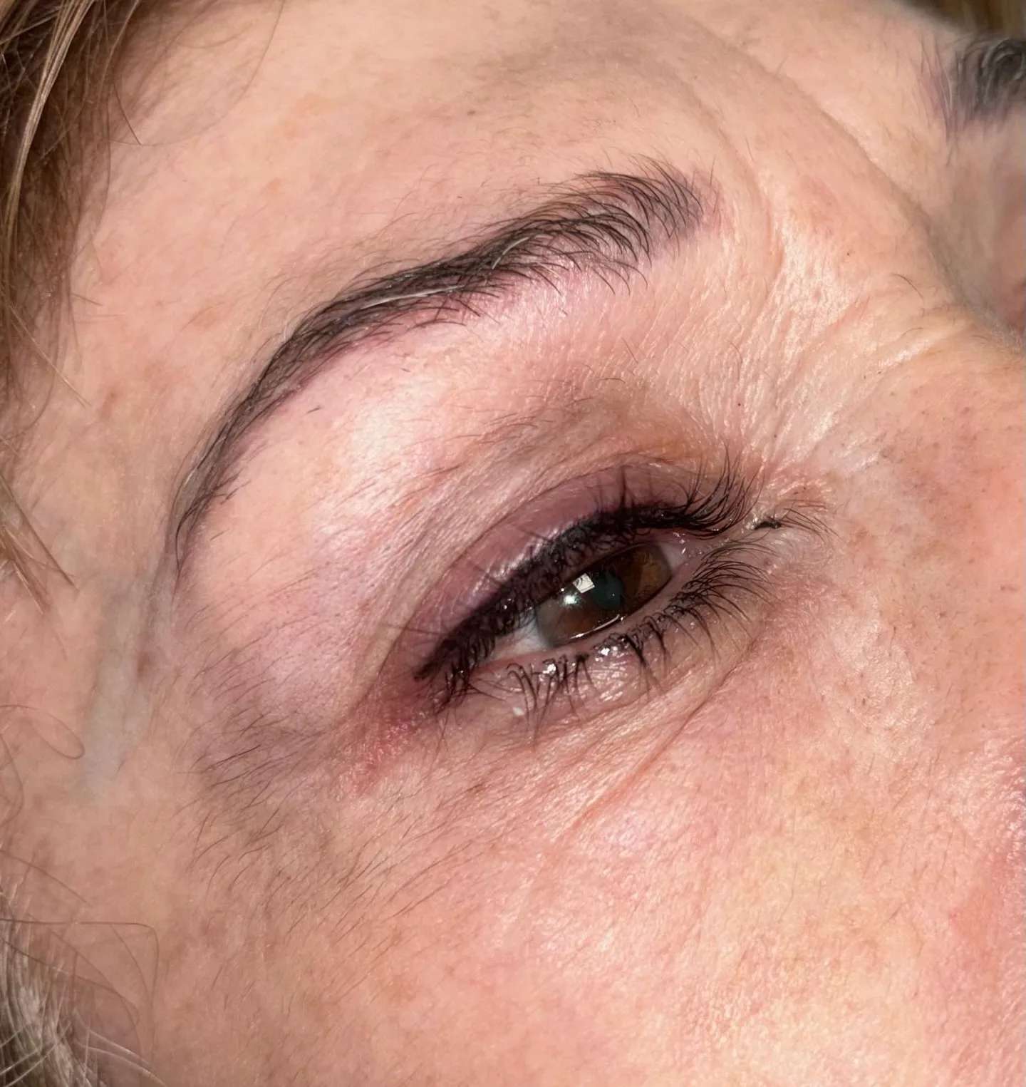 Primer plano de la mirada de una clienta con la ceja micropigmentada pelo a pelo en el centro